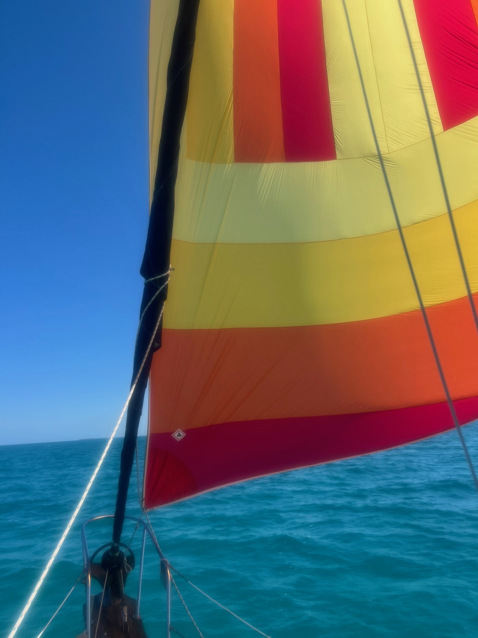 Colorful spinnaker flying underway in turquoise water